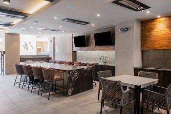 a dining room with tables and chairs and a counter with televisions